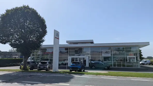 Le Garage Mononk vu depuis la chaussée : totem Citroën, showroom vitré et véhicules exposés